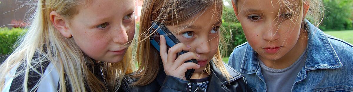 Drie meisjes van 8 en 9 jaar aan de telefoon tijdens het kinderfeestje.